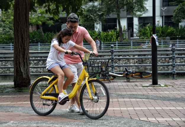 photography of girl riding bike beside man